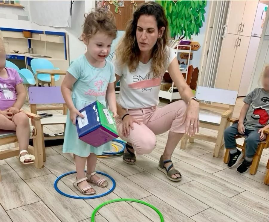 אשת צוות וילדה בפעילות תנועה עם חישוקים