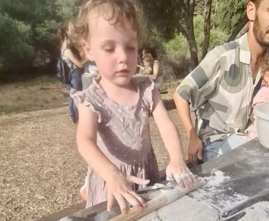 ילדה לשה בצק על שולחן בחוץ