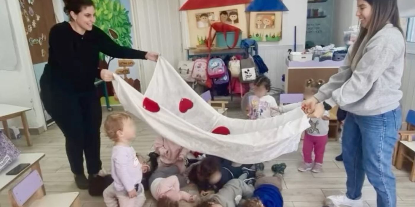 אנשי צוות מניפים יריעה מעל ילדים בכיתה