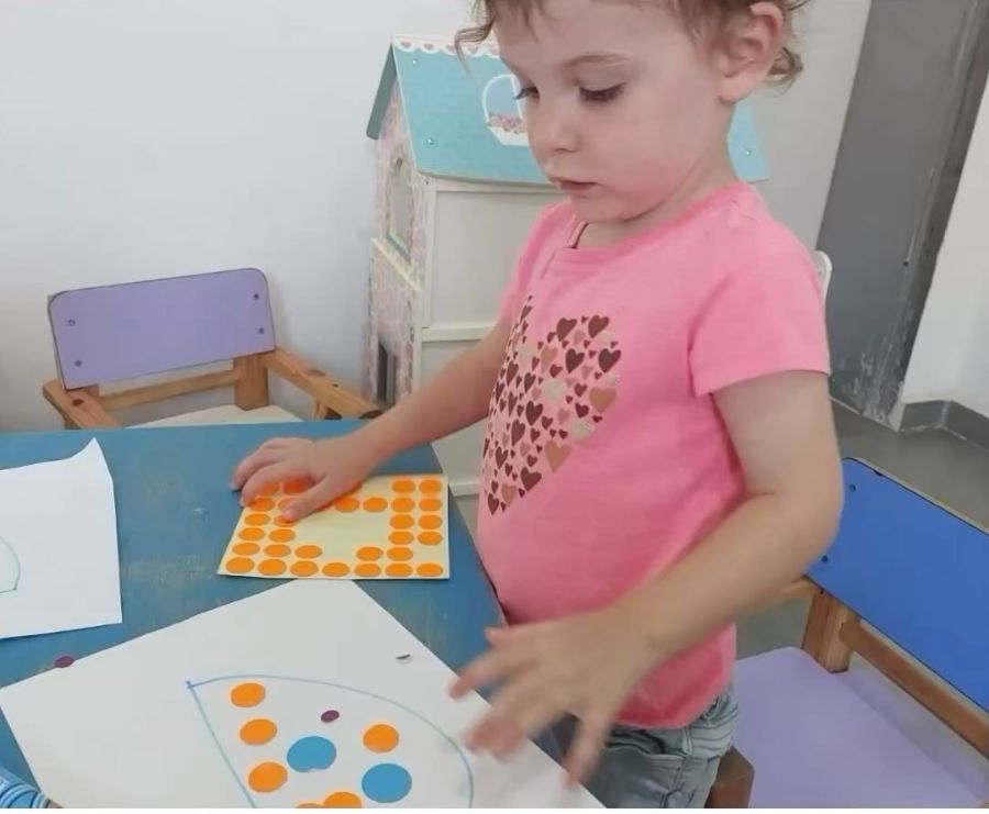 ילדה מדביקה מדבקות עגולות בעבודת מוטוריקה עדינה