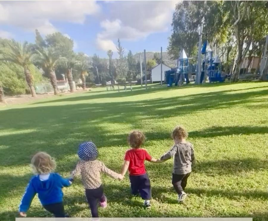 ארבעה ילדים אוחזים ידיים ורצים בדשא
