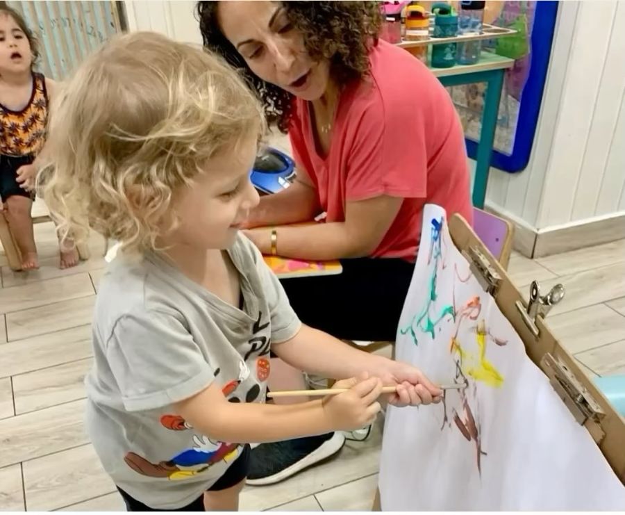 ילד מצייר על כן ציור לצד אשת צוות