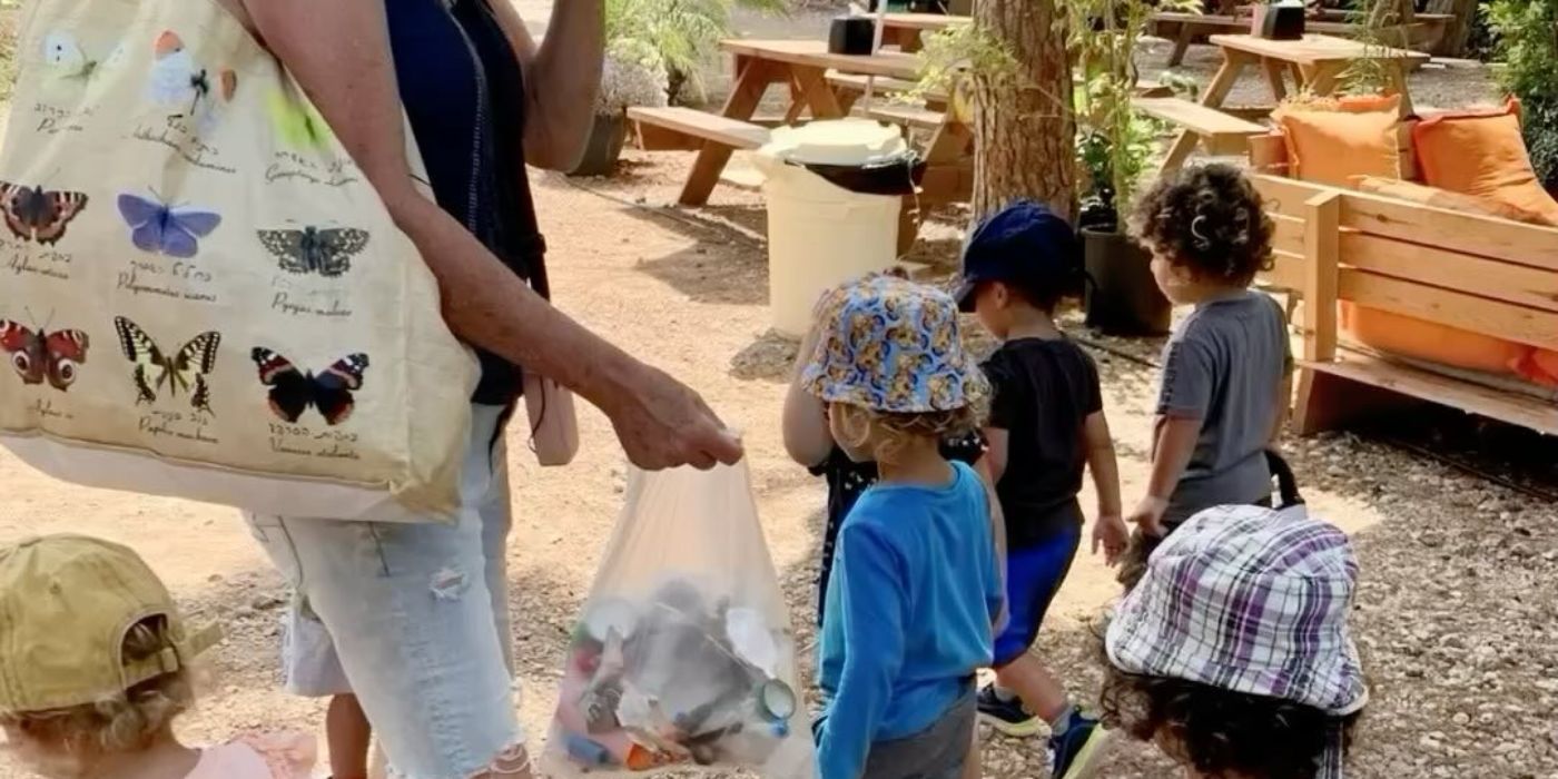 אשת צוות וילדי הגן הולכים בחוץ ואוספים פסולת