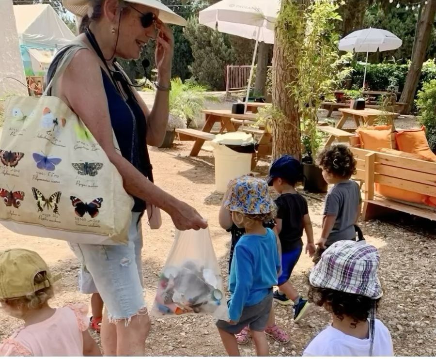 אשת צוות וילדי הגן אוספים פסולת בטיול
