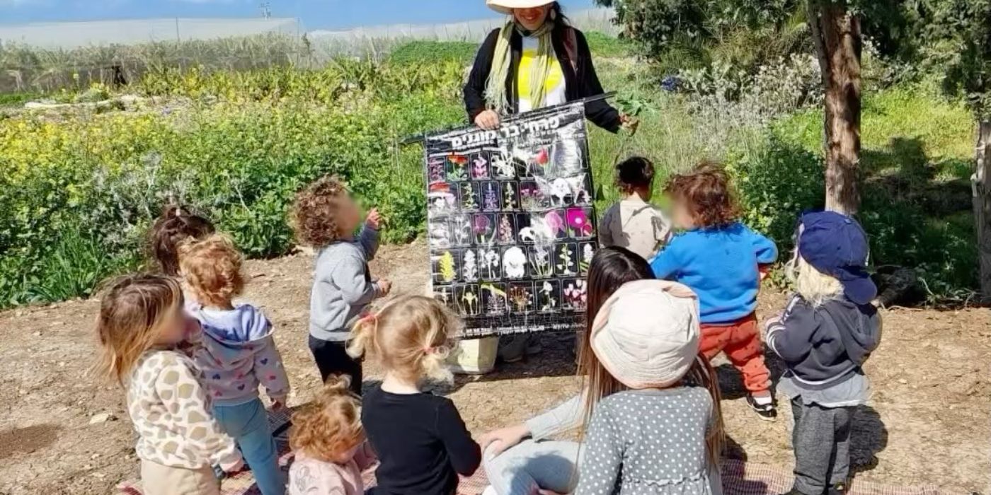 ילדים ואשת צוות סביב עגלת תצוגה בשדה