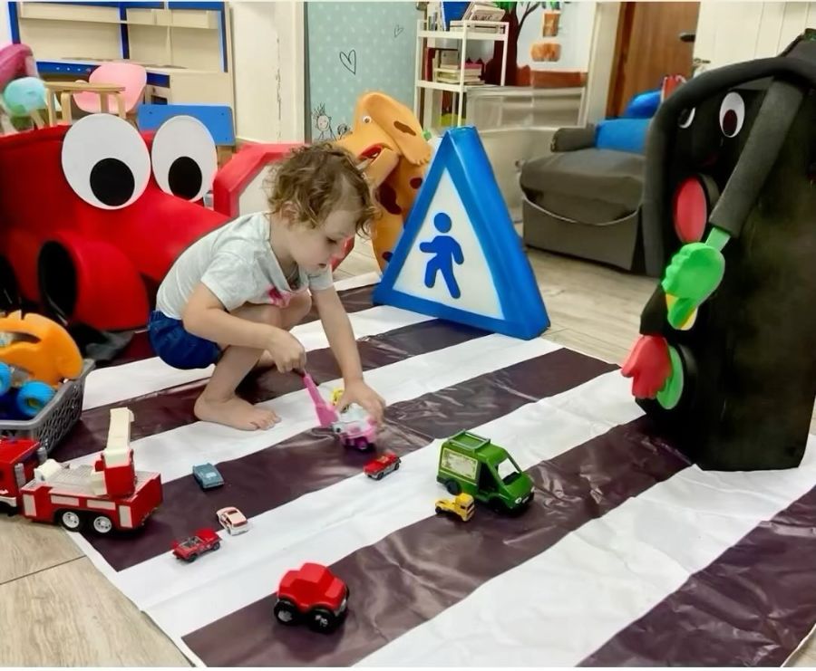 ילד משחק במעבר חצייה עם מכוניות צעצוע