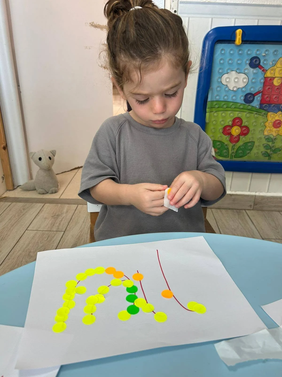 ילדה מתנסה ביצירה ובהדבקה בגן