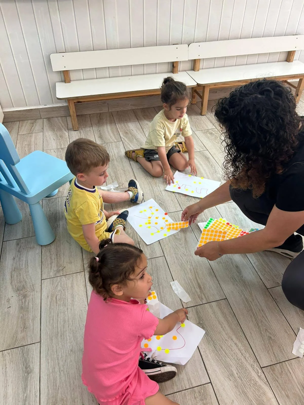 אשת צוות מלווה ילדים בפעילות יצירה בגן